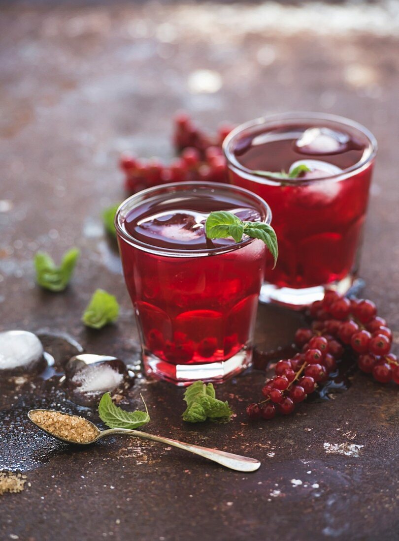 Red berry lemonade with ice and mint on vintage rusty metal backdround