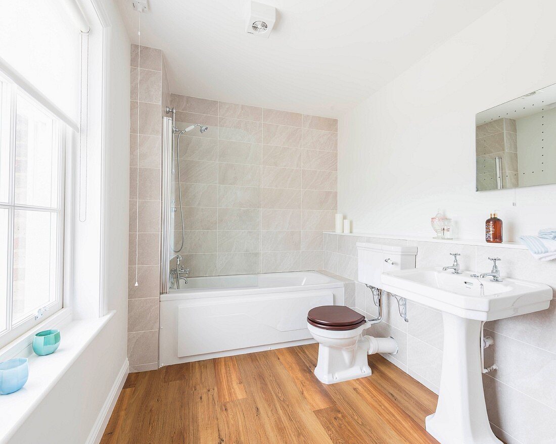 A bright bathroom with a washbasin, a toilet and a bathtub