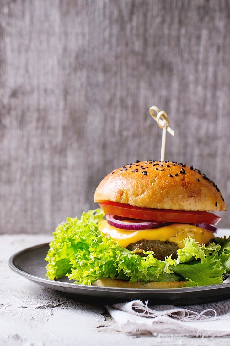 Hausgemachter Hamburger mit schwarzem Sesam auf Zinnteller