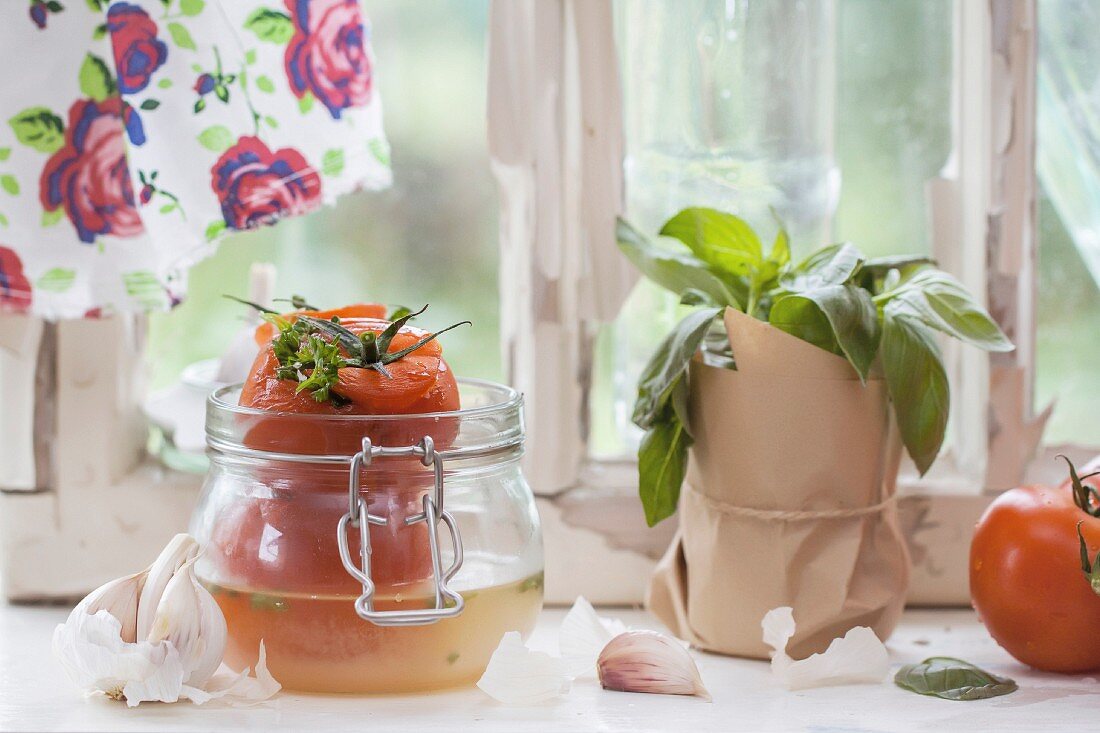 Canned tomatoes and basil on old windowsill in nature light