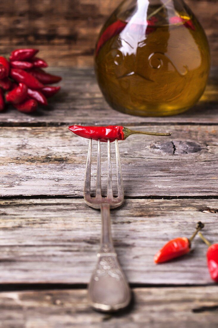Red hot chili pepper on vintage fork over old wooden background