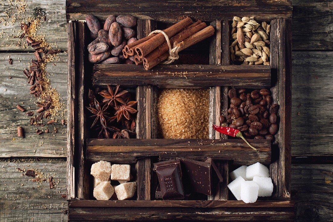 Coffee and cocoa beans, sugar cubes, dark chocolate, cinnamon and anise over wooden background