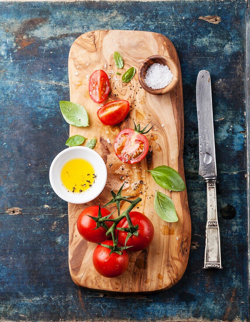 Sliced ​​ripe tomatoes on olive wood cutting board on blue background