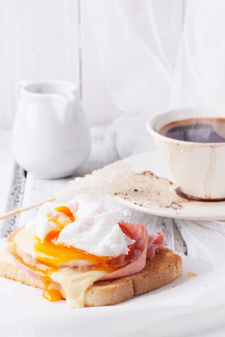 Frühstück mit einer Tasse Kaffee und Schinken-Käse-Toast mit pochiertem Ei