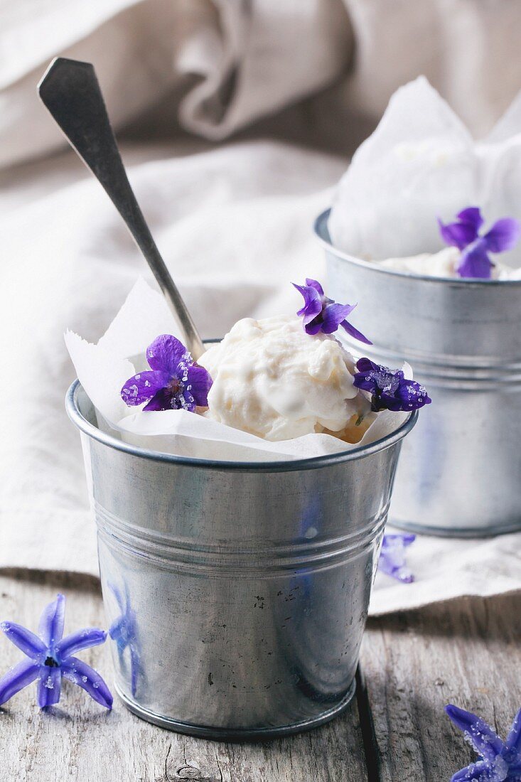 Ice cream, served in little metal pail with sugared violets on old wooden table