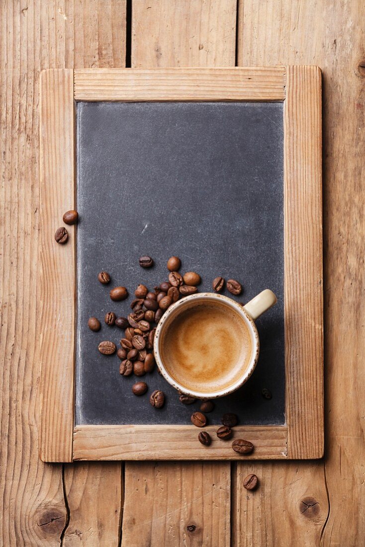 Coffee cup with coffee beans on vintage slate chalk board