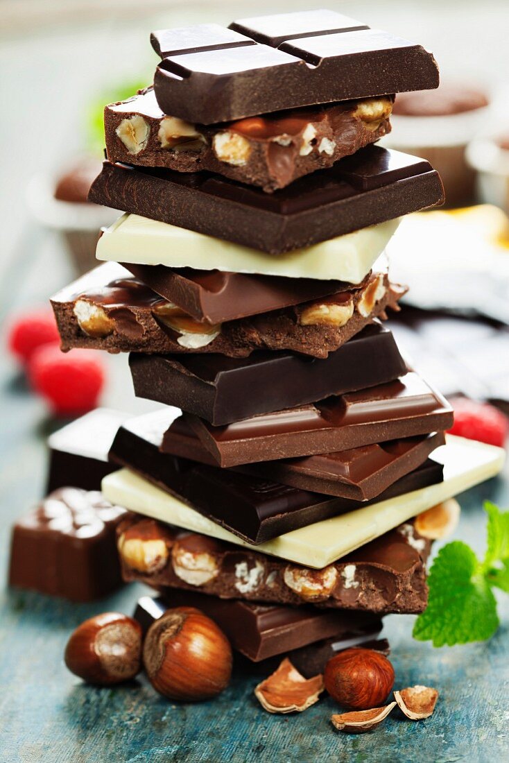 An assortment of white, dark, and milk chocolate with nuts on wooden background