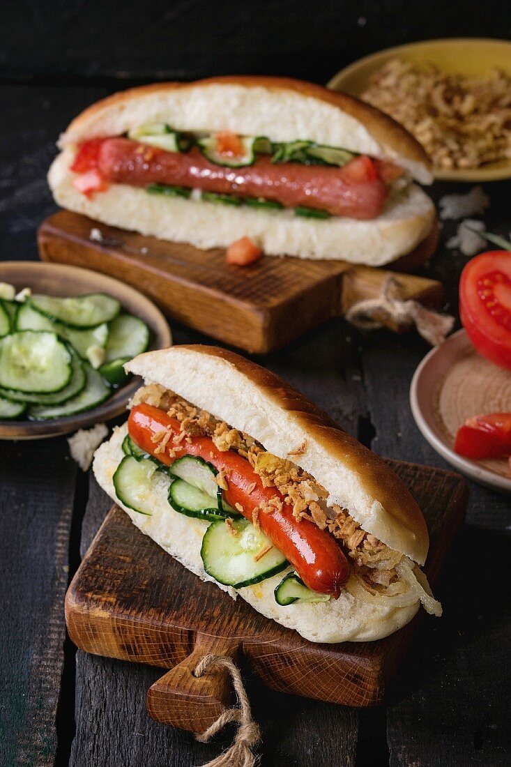 Two of homemade hot dogs with sausage, fried onion, tomatoes and cucumber