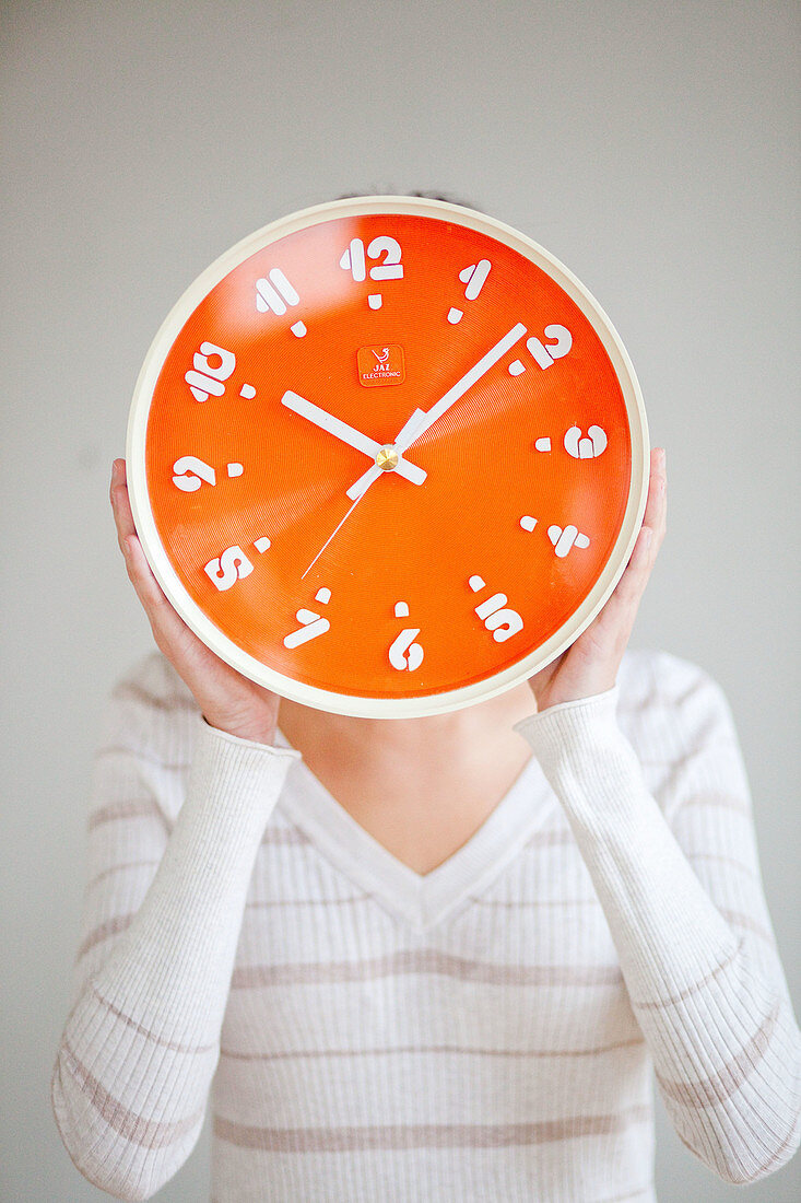 Woman holding orange clock