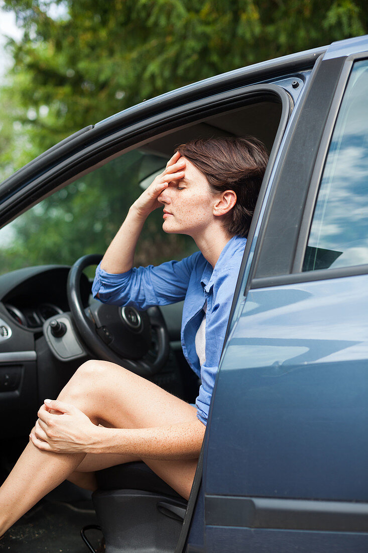 Woman with headache in her car