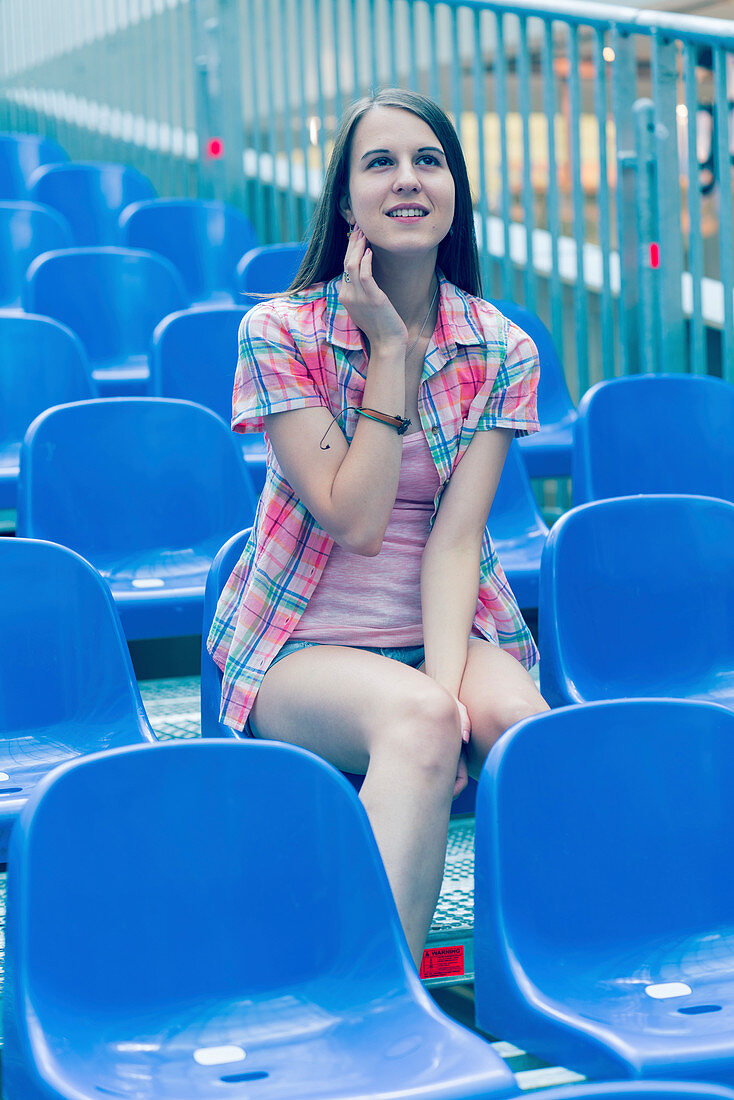 Young woman sitting on blue plastic seat