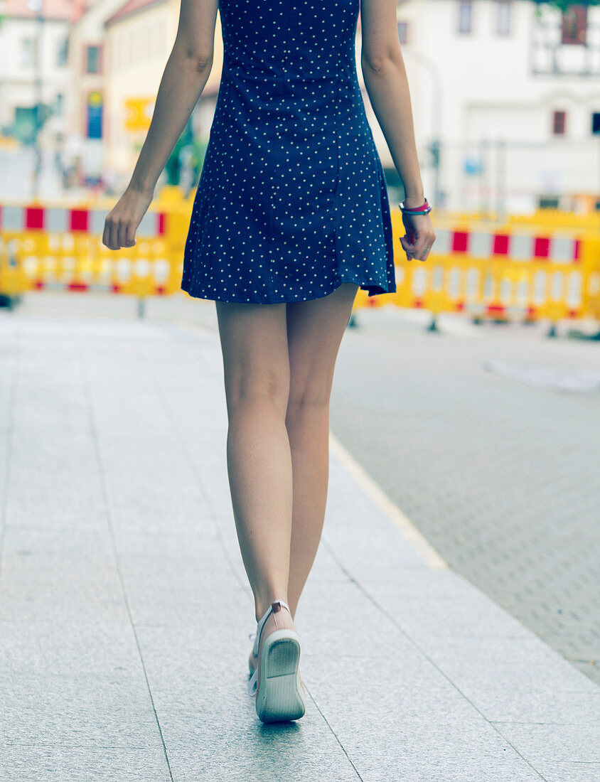 Young woman in short dress walking on pavement