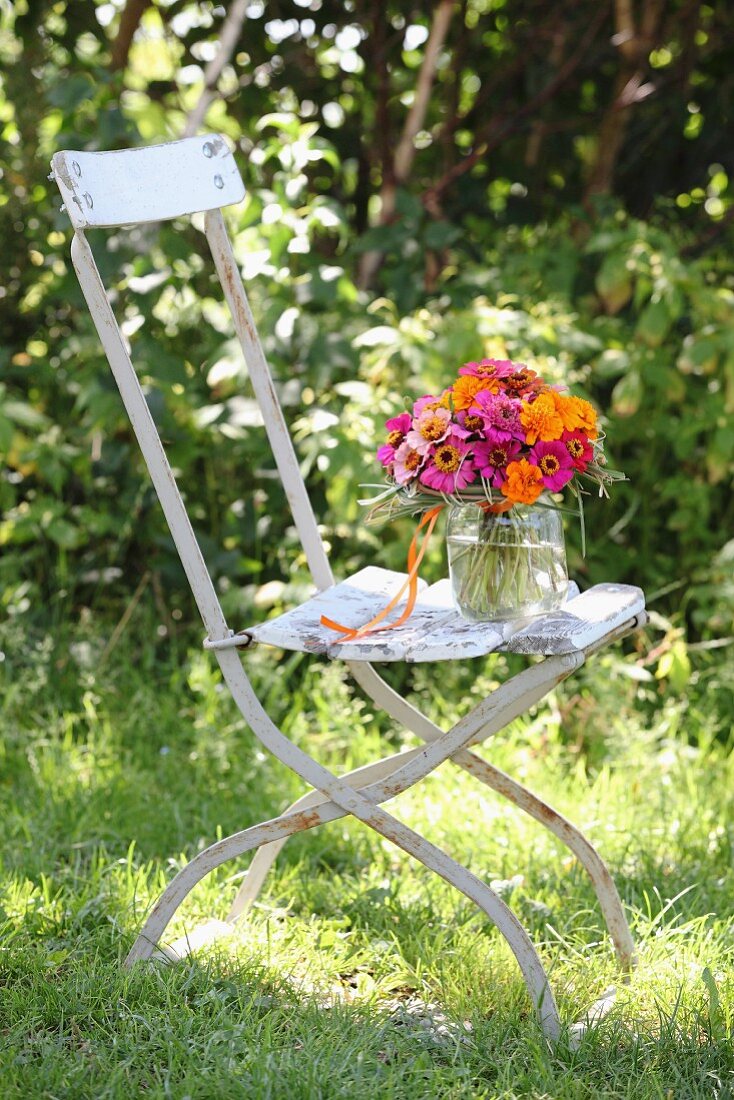 Farbenfroher Blumenstrauss mit Zinnias und Tagetes auf Vintage Gartenstuhl