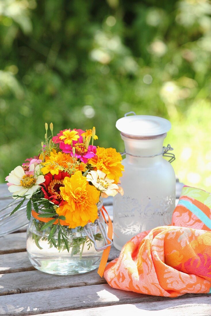 Bunter Blumenstrauss mit Tagetes und Zinnias auf Gartentisch