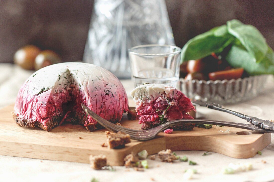 Delicious snack salad herring under a fur coat on wooden board with fork and russian vodka