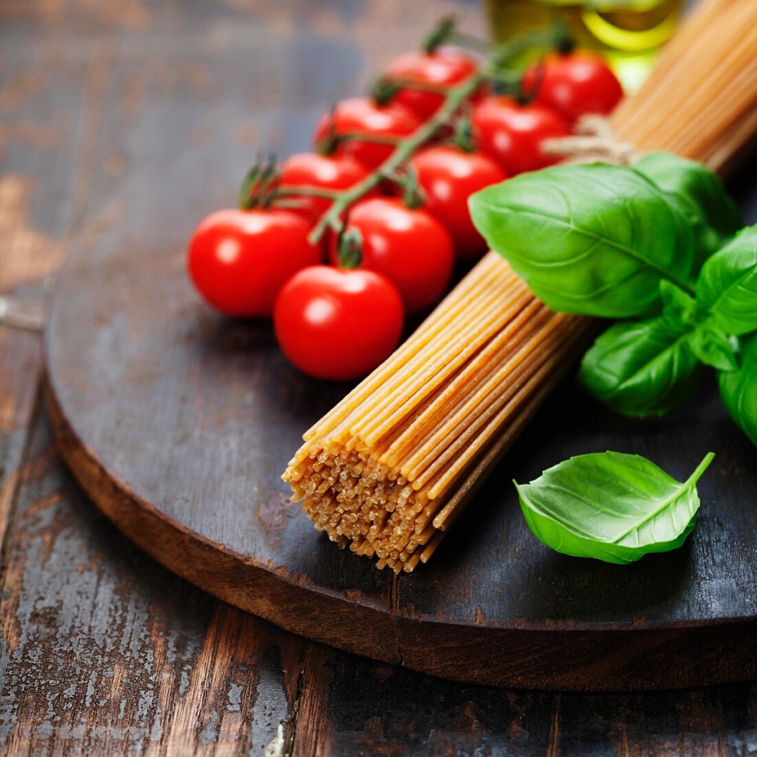 Spaghetti, Tomaten und Basilikum auf einem altem Holztisch