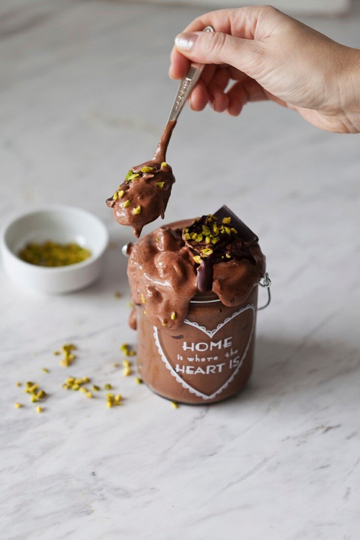 Vegan chocolate banana ice cream with melted dark chocolate and pistachios in a jar