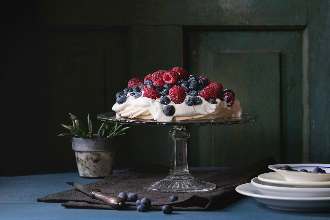 Pavlova mit Heidelbeeren und Himbeeren auf Vintage-Kuchenständer