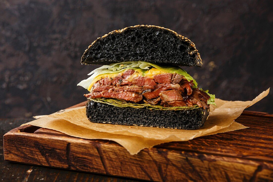 Cut in half Roast beef Burger with sliced Pastrami on dark background