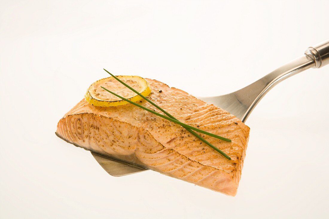 Salmon filet with roasted lemon slice and chives on a spatula