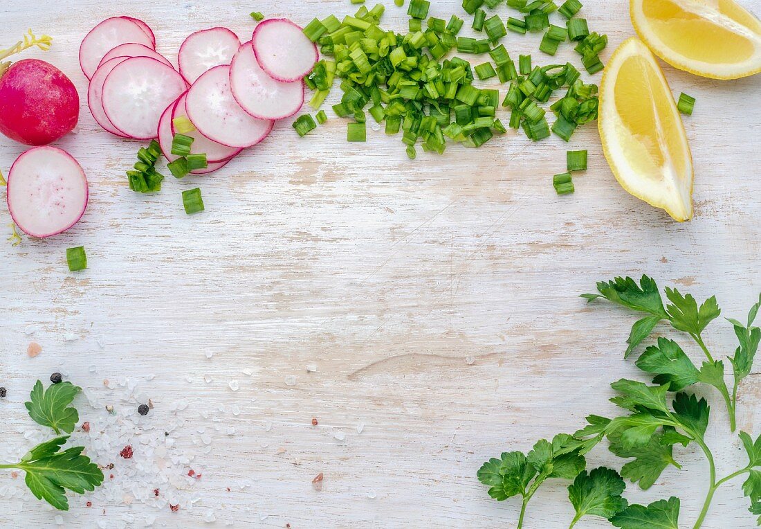 Radish, green onion, parsley and lemon slices on white painted wooden background