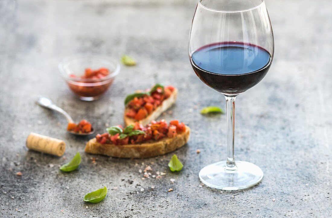 Glas Rotwein und Häppchen mit Tomaten und Basilikum