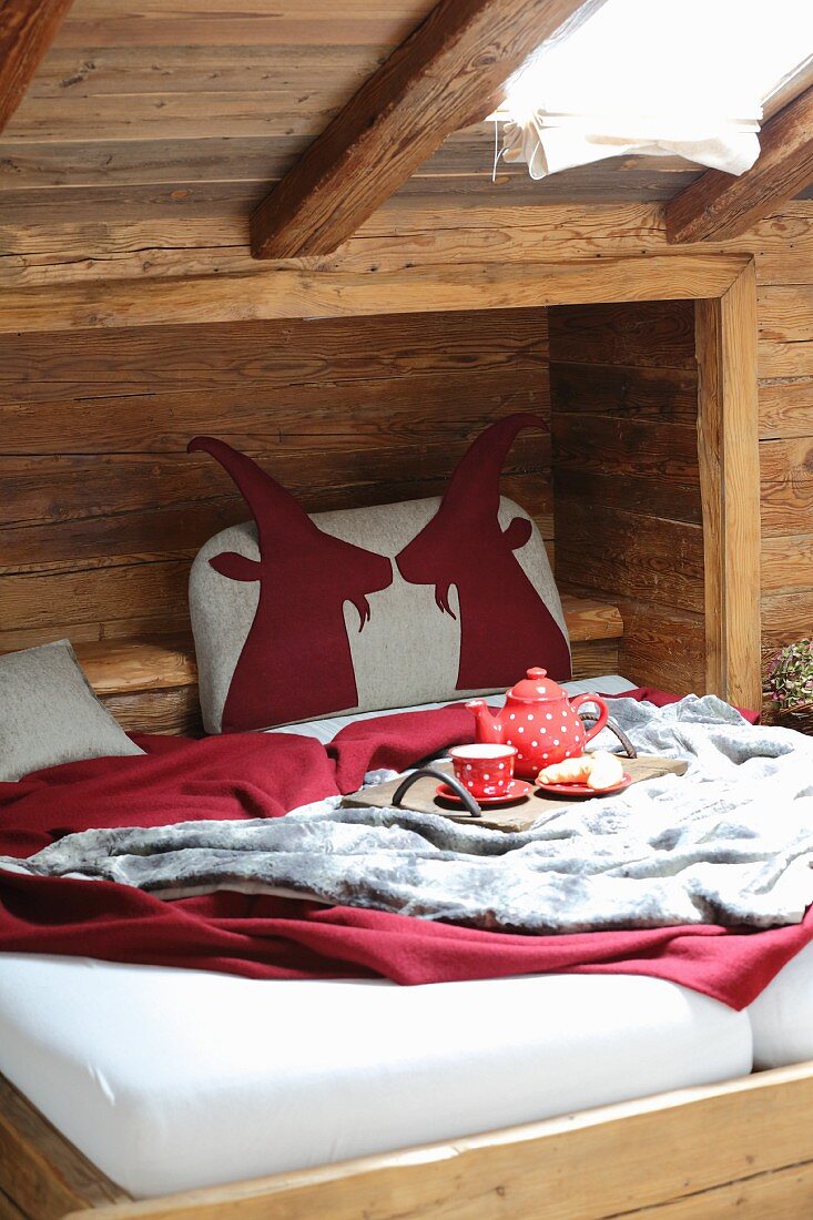 Bettkopfteil mit Tiermotiven aus rotem Filz in rustikaler Bettnische