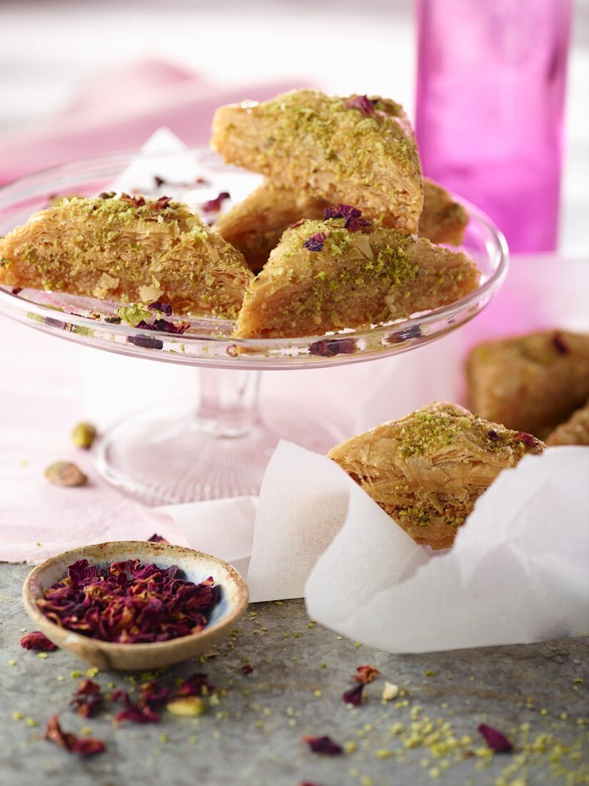 Pistachio baklava with rose petals on cake stand with pink napkin