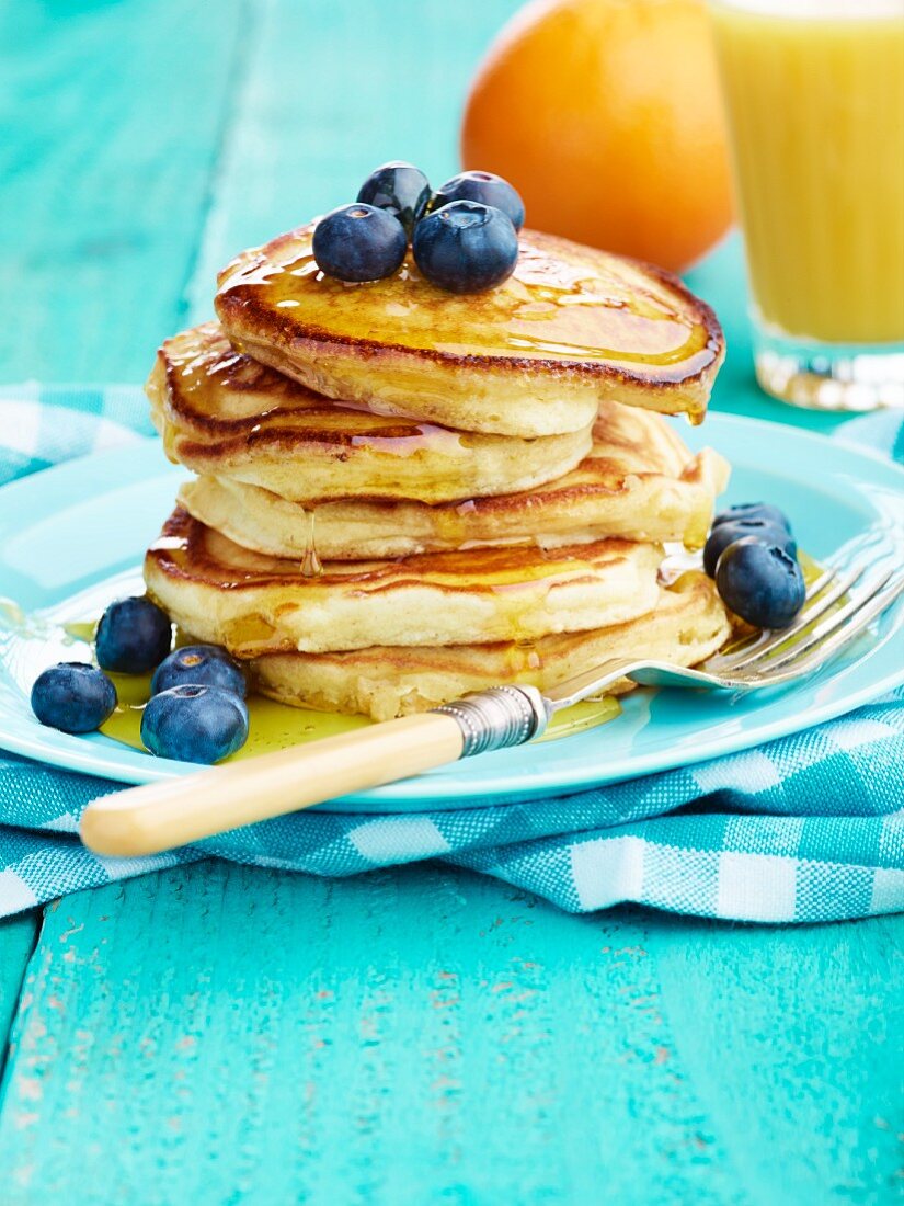 Pancake stack with maple syrup and blueberries and orange juice