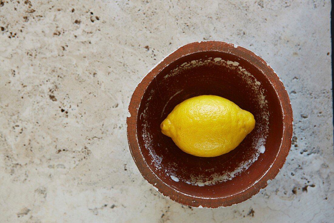 Zitrone in Vintage-Schüssel auf rustikalem Marmortisch