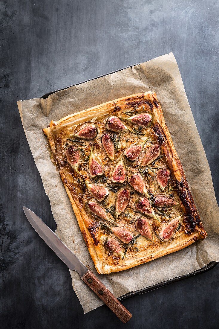 Fig blue cheese and rosemary tart on baking tray with knife