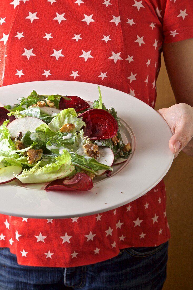 Girl serving apple, greens, red beet and walnut salad with buttermilk dressing