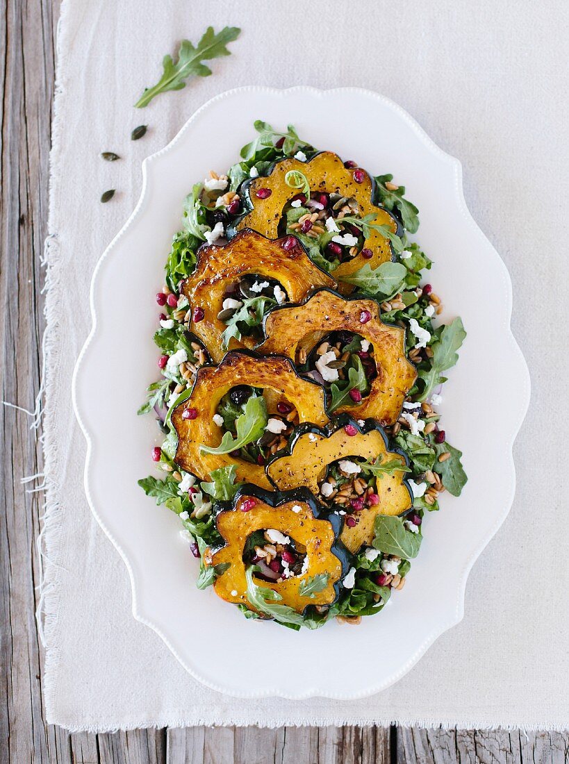 An oval salad plate of Roasted Acorn Squash Salad with Spicy Pepitas and Cranberries