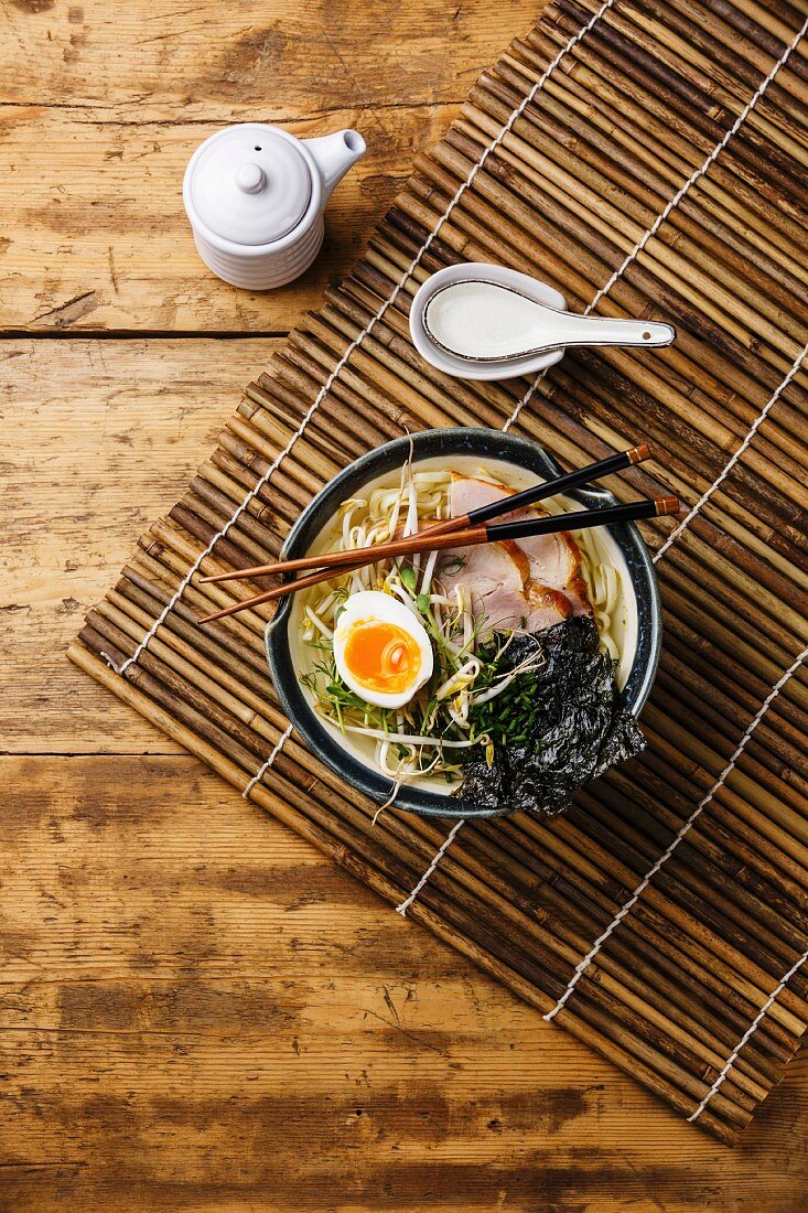 Udon noodle with boiled pork, wheat germ and egg on wooden background