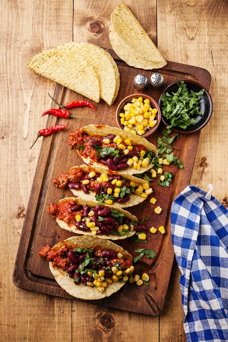 Tacos with ground beef, corn and red beans on wooden table