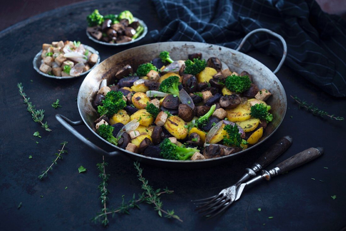 Vegane Gemüsepfanne mit violetten und gelben Kartoffeln, Brokkoli, Champignons, Tofu und Schalotten