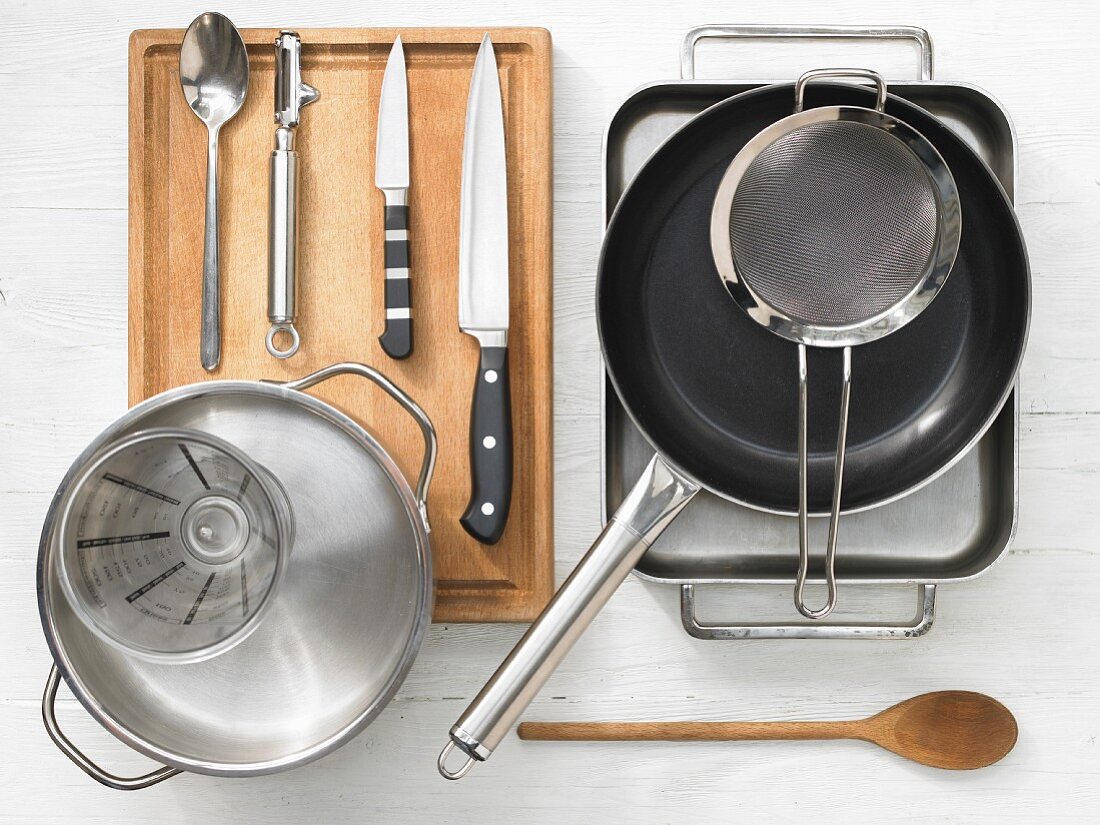 Various kitchen utensils: baking dish, pan, sieve, pot, measuring cup, knives