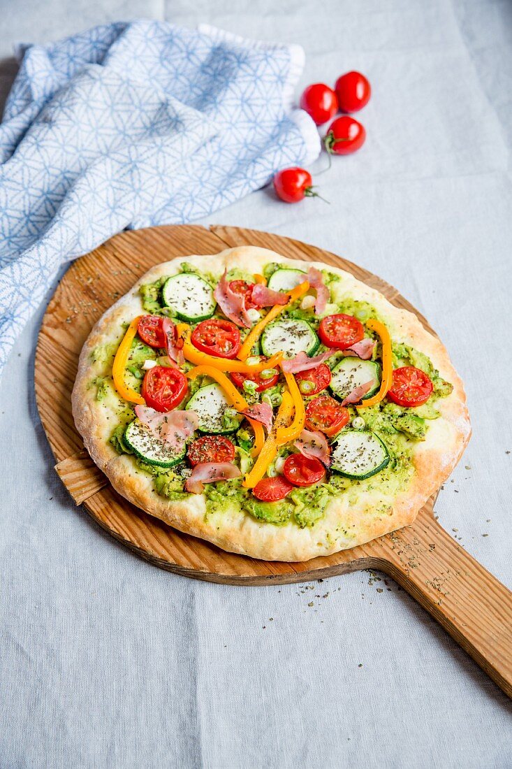 Pizza mit Avocado, Zucchini, Tomaten, Paprika und Schinken