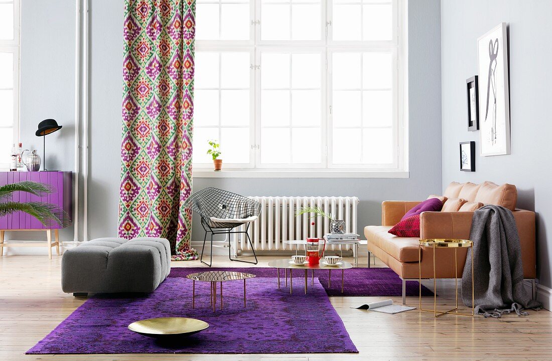 Wohnzimmer mit Ledersofa und lila Teppich in Altbauwohnung