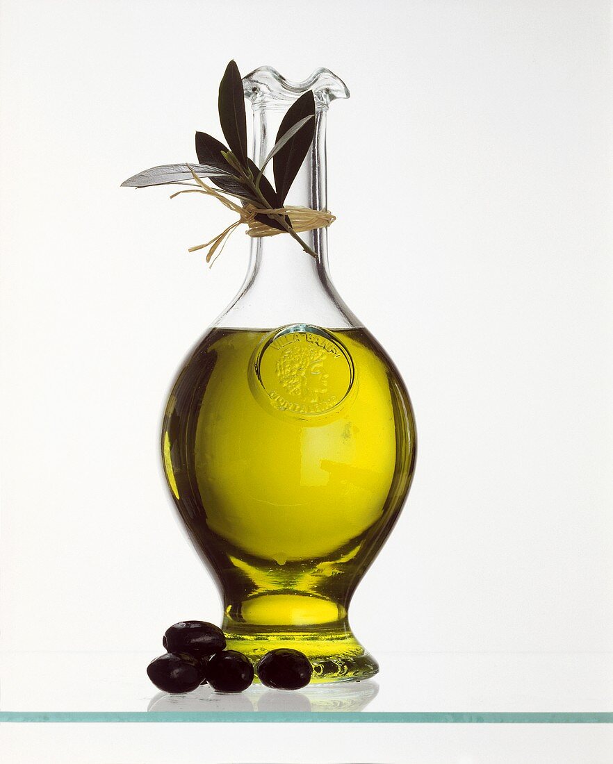 A glass bottle of olive oil and fresh olives