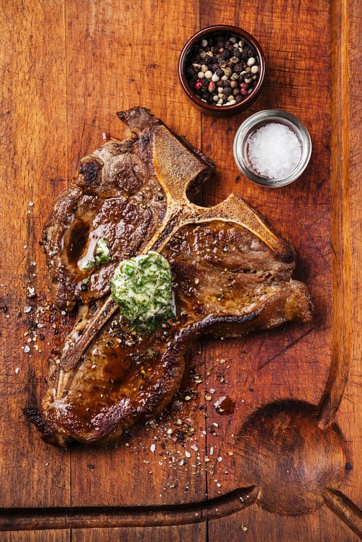Grilled T-Bone Steak and herb butter on wooden cutting board