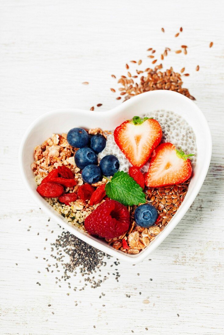 Healthy breakfast of muesli, berries with yogurt and seeds on white background