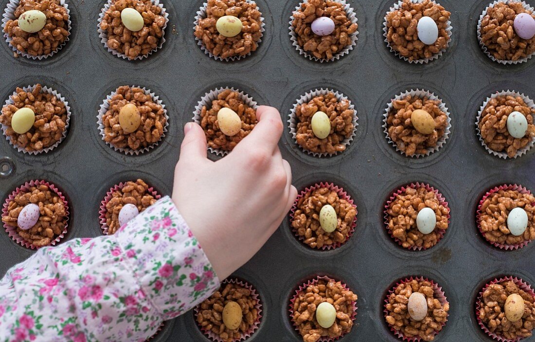 A childs hand selecting an Easter chocolate krispy cake