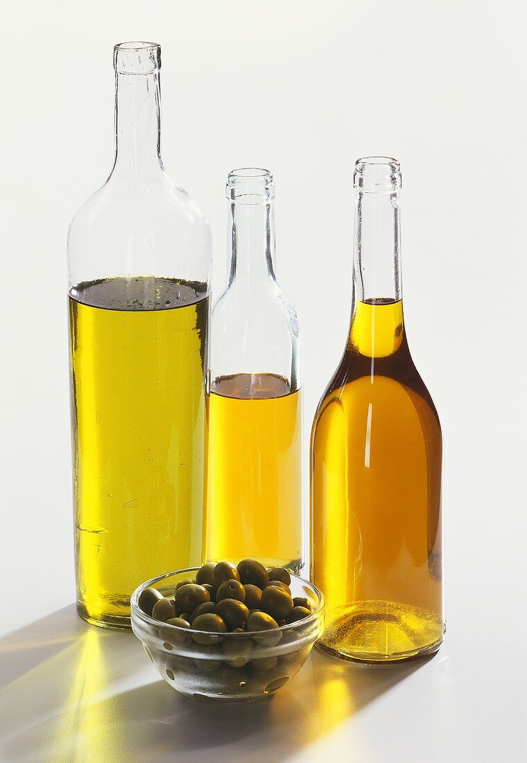 Three bottles of olive oil and green olives