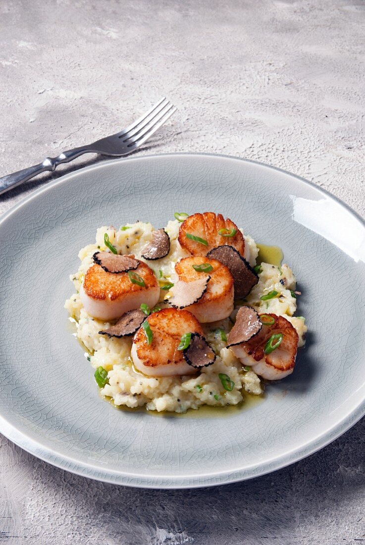 Seared scallops served on a bed of mashed parsnips with sliced truffles