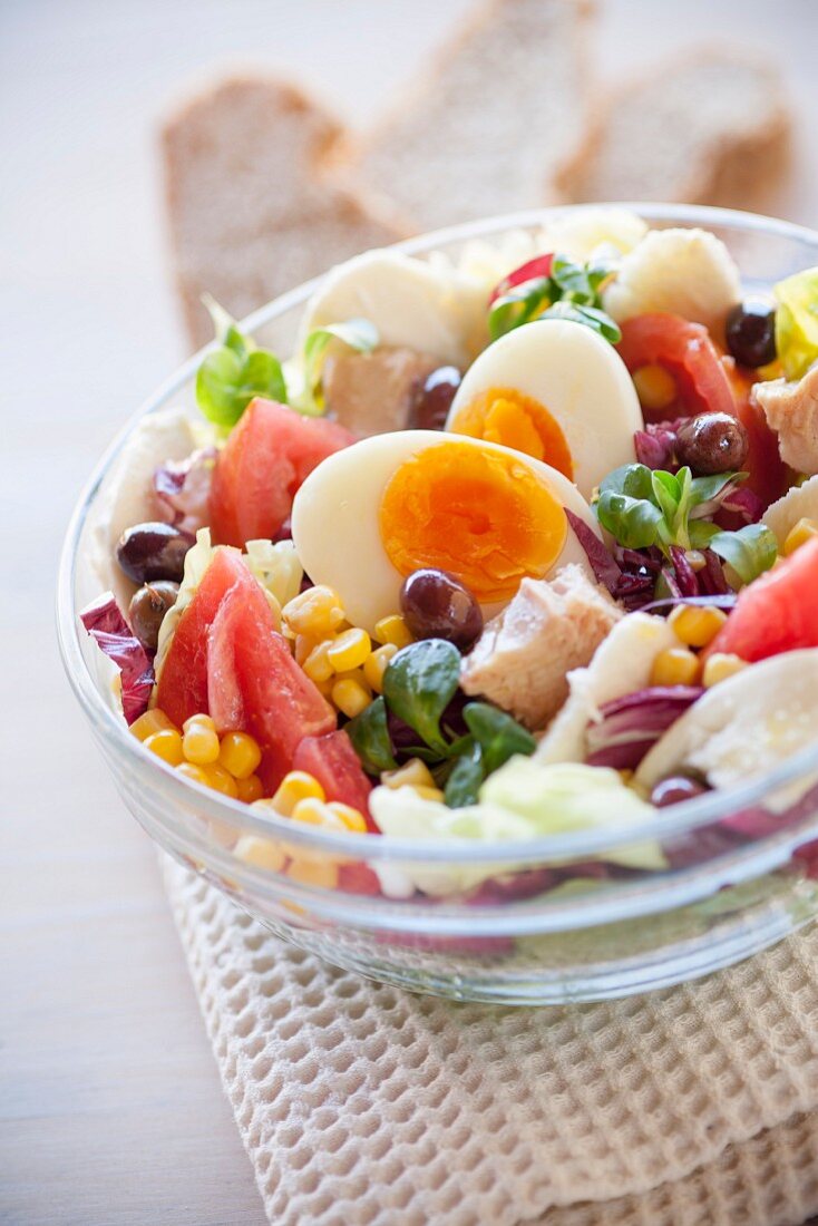 Salatschüssel mit Tomaten, Mais, Thunfisch, gekochtem Ei, Oliven, Mozzarella, Radicchio und Feldsalat