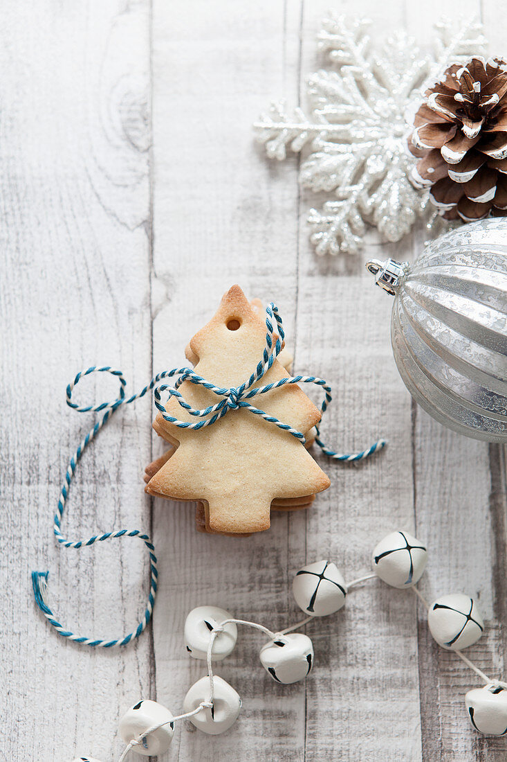Stack of Christmas Tree shaped biscuits tied with blue and white bakers twine on a white wood rustic christmas setting