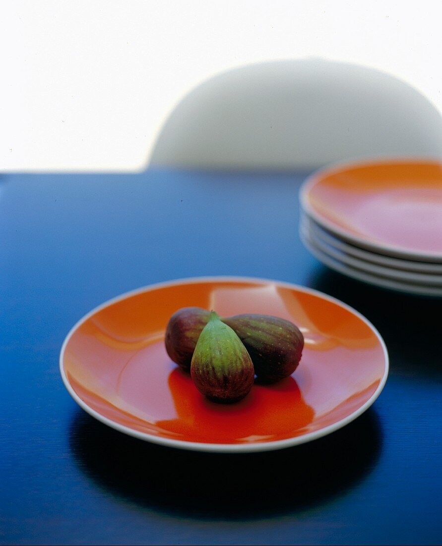 Frische Feigen auf orangefarbenem Teller auf blauem Tisch