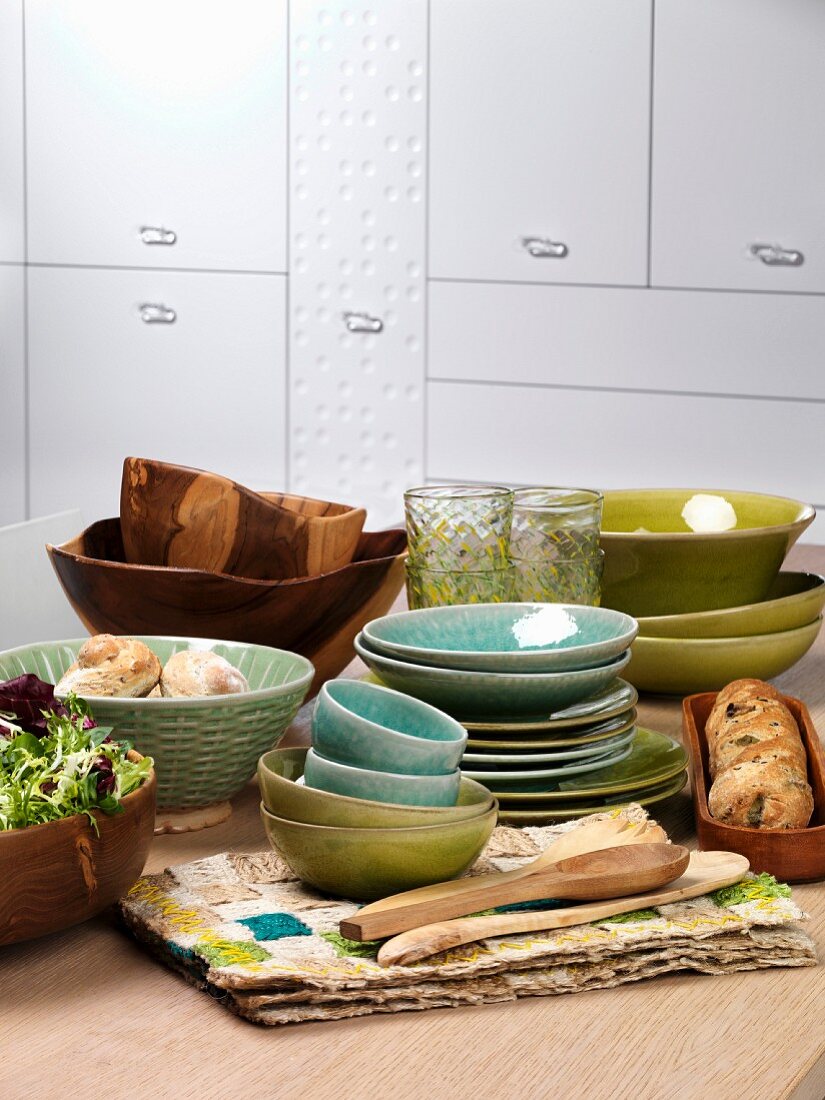 Bowls and plates with bread and salad on a kitchen table