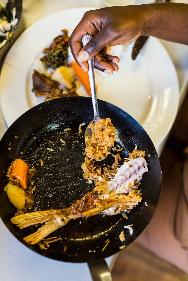 Remains of fried fish with wild rice and vegetables in a pan (South Africa)